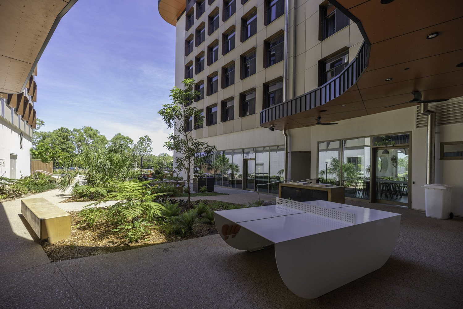 JCU Student Accommodation Exterior Common Use Area With Ferns Ping Pong Table Trees And Blue Sky