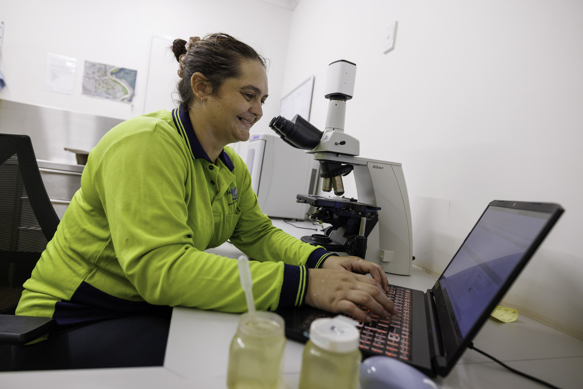 Humpty Doo Barramundi Worker Typing On A Keyboard And Conducting Research With A Microscope In An Office