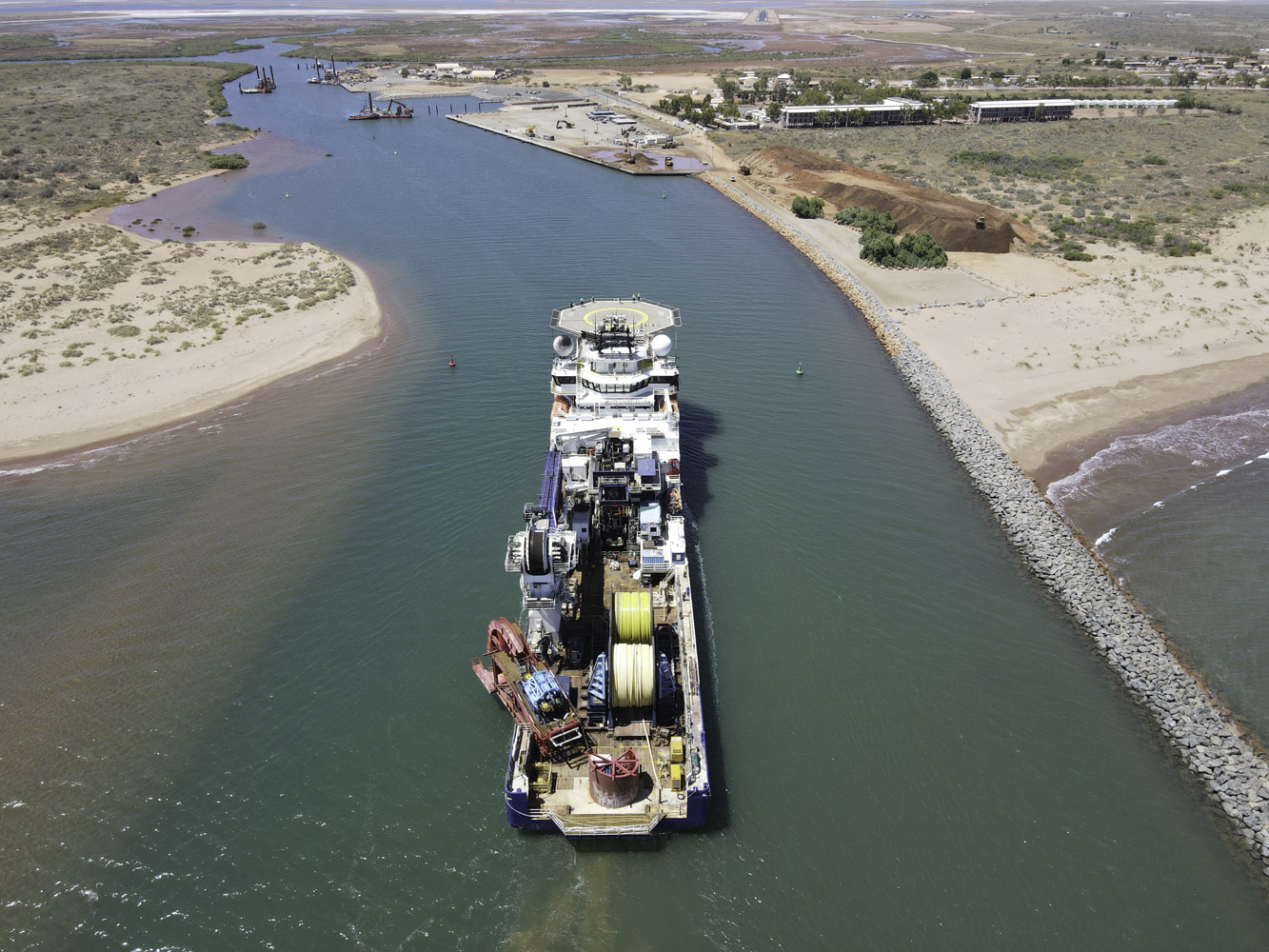 Onslow Marine Support Base Large Ship With Helipad And Yellow Wire Spindles Cruising Into River Opening