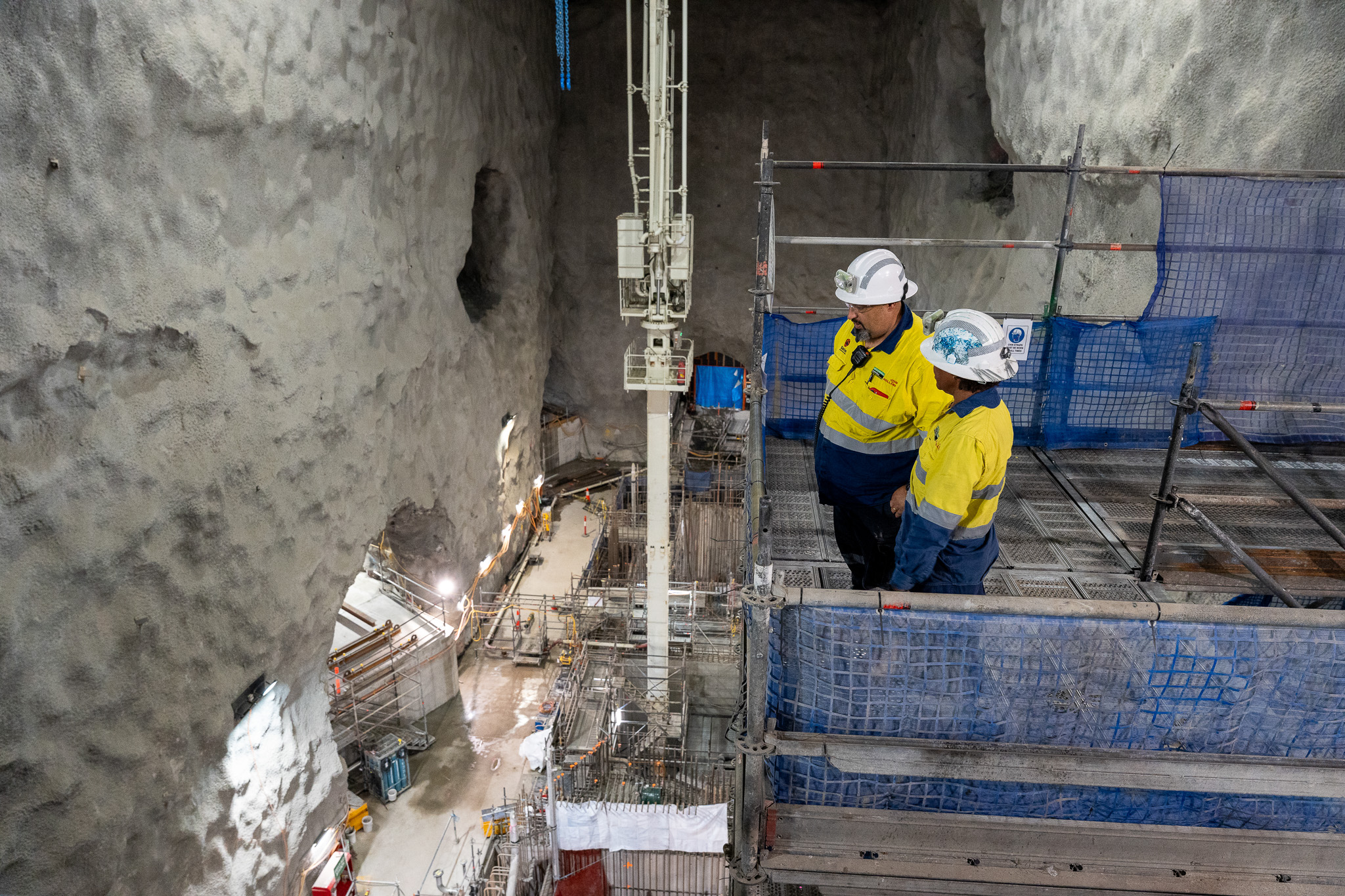Ross Rosas speaking to supervisor underground at the Genex Kidston Pumped Storage Hydro Project with safety PPE helmet, light, hi-vis shirt and glasses