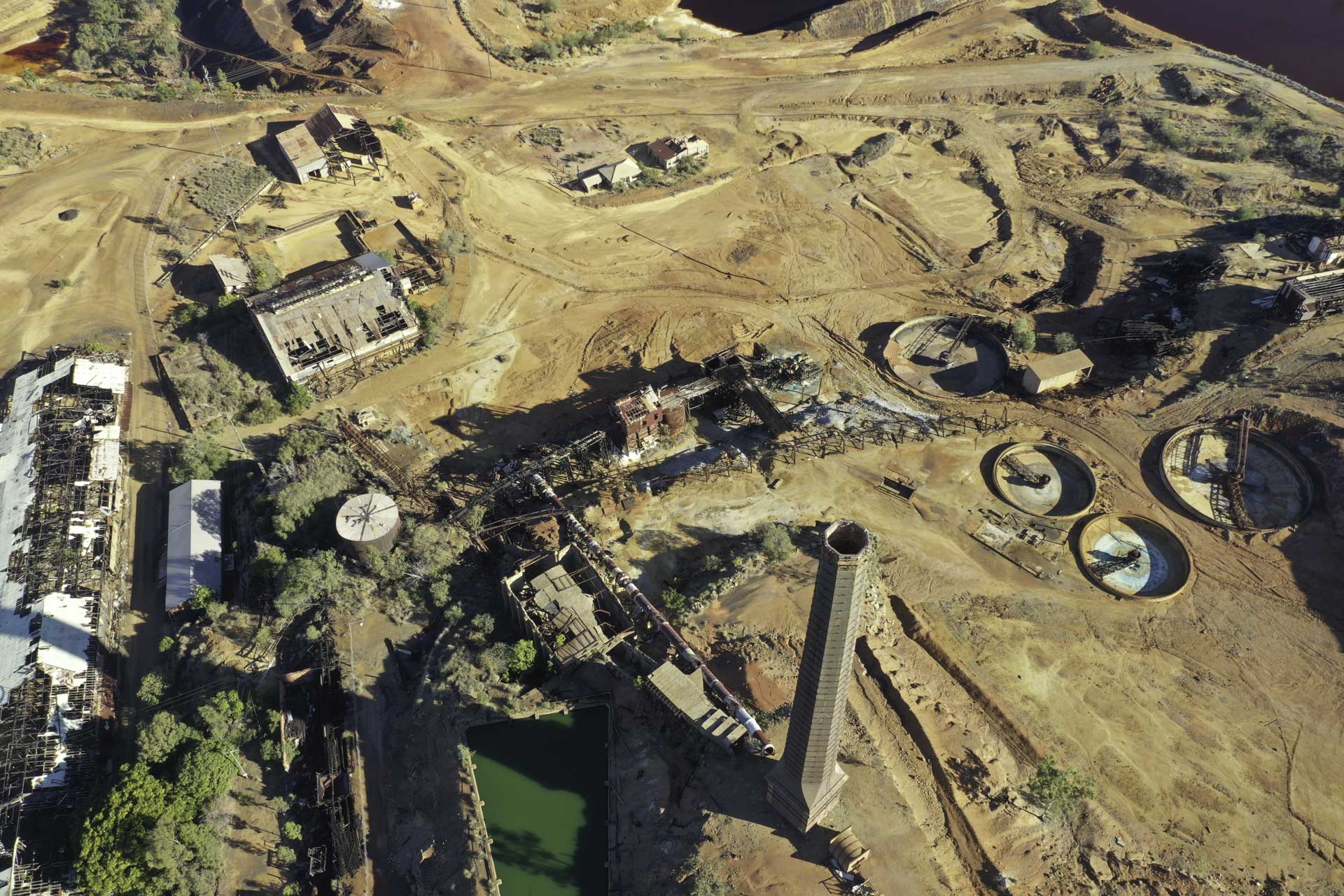 Heritage Minerals Mount Morgan Gold And Copper Tailings Reprocessing And Rehabilitation Aerial View Looking Down Over The Top Of The Old Mine Site With Chimney Stack And Empty Water Treatment