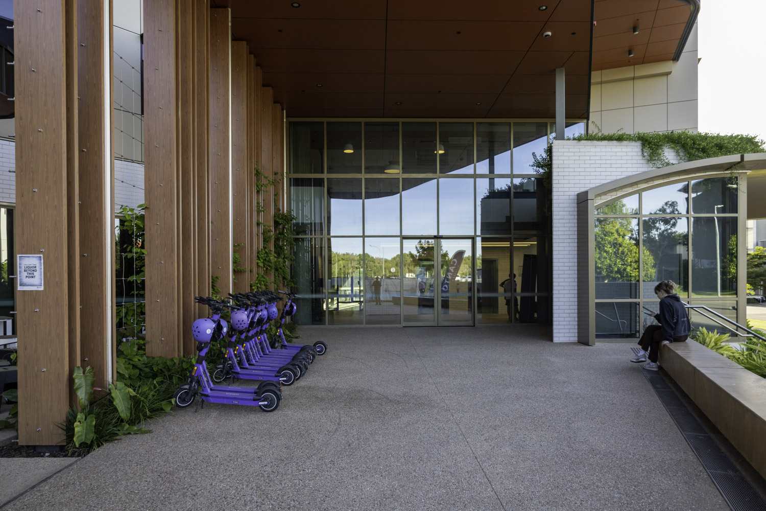 JCU Student Accommodation Main Entrance With Timber Laminate Pillars Glass Fascia Concrete Flooring And Purple Scooters