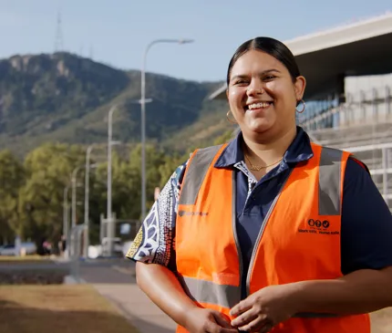 Breeanne Saltner in hi vis jacket smiling with mount stuart and construction site in the background