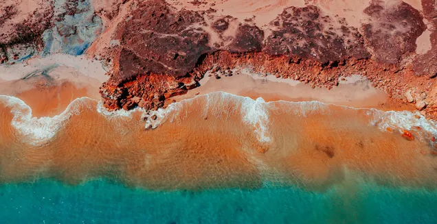 Vivid Red Rockface Adjacent To Blue Ocean In Broome Western Australia