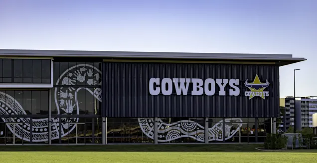 NQ Cowboys Community, Training and High-Performance Centre front view of exterior with indigenous snake artwork on glass and cowboys logo with grass in the foreground